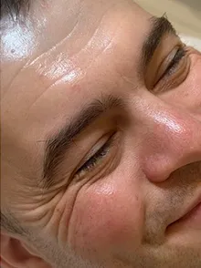 Nahaufnahme eines lächelnden Mannes mit sichtbaren Lachfalten um die Augen und Stirn.