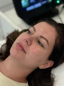 Frau liegt mit geschlossenen Augen entspannt auf einer Behandlungsliege, Blick zur Seite gerichtet.