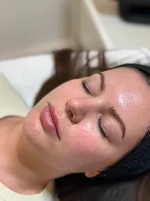 Frau mit geschlossenen Augen und sauberer, glänzender Haut trägt ein schwarzes Stirnband.