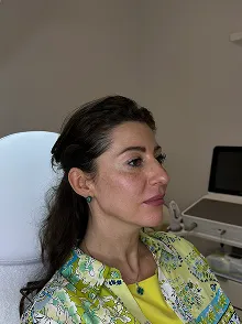 Portrait einer Frau mit dunklen Haaren in einer medizinischen Umgebung.