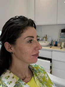 Seitenansicht einer Frau mit langen dunklen Haaren in einem Raum mit weißer Kücheneinrichtung.