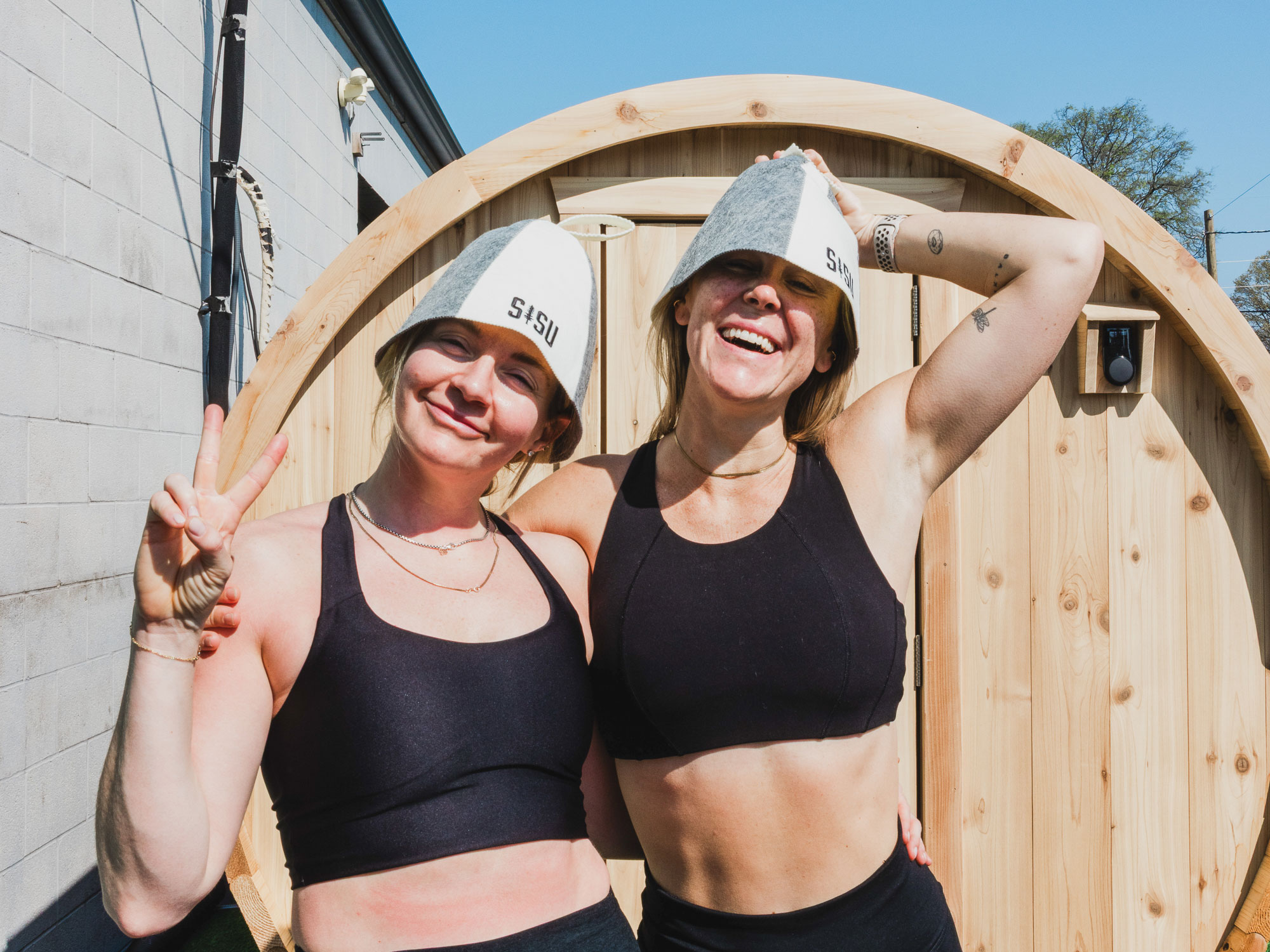 Two happy athletes smiling for the camera in front of a sauna.