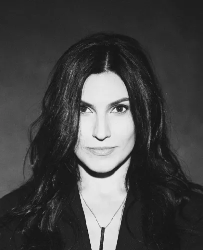 Black and white portrait of a woman with shoulder-length dark hair looking directly at the camera against a dark background.