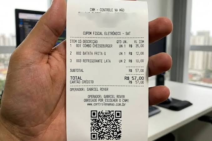 Cupom fiscal segurado na mão, capturado pela câmera do app