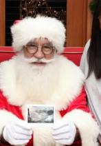 Portrait of Santa Claus wearing glasses, a red hat, and a fluffy white beard.