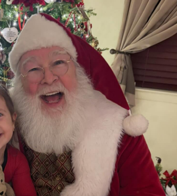 Close-up of Santa Claus with white beard and red hat smiling.