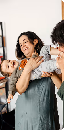 A couple happily holds a toddler in their arms.