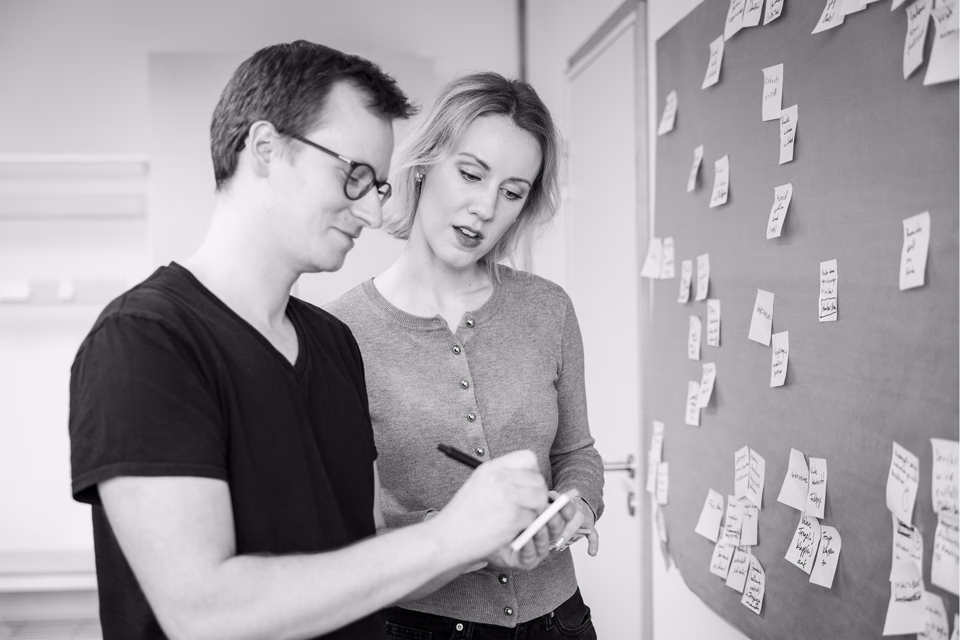 Zwei Mitarbeitende von int[cube] bei einem Workshop zur Cybersecurity-Due-Diligence mit Post-its an der Wand
