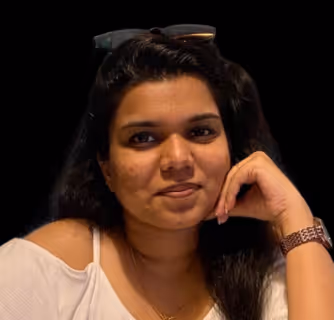 Woman with long dark hair resting her chin on her hand, wearing a white off-shoulder top and a watch.
