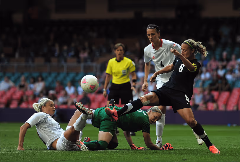 Bex Smith, wearing the captain’s armband for New Zealand, competing for possession near the goal in an international women’s football match.