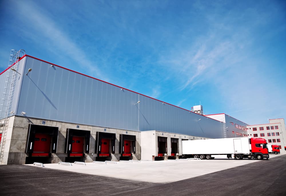 Commercial warehouse and distribution facility with loading docks and trucks, representing assets protected by commercial property insurance.