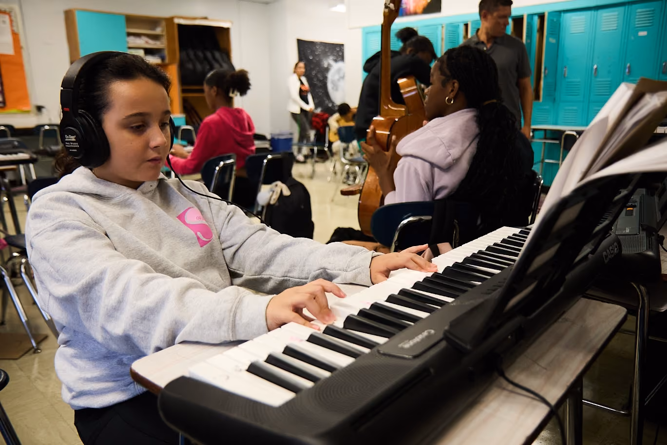 Student wearing headphones plays keyboard in music class