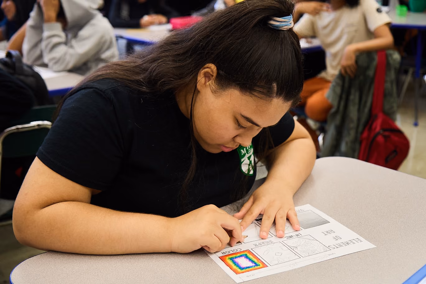 Student working on an elements of art worksheet at her desk