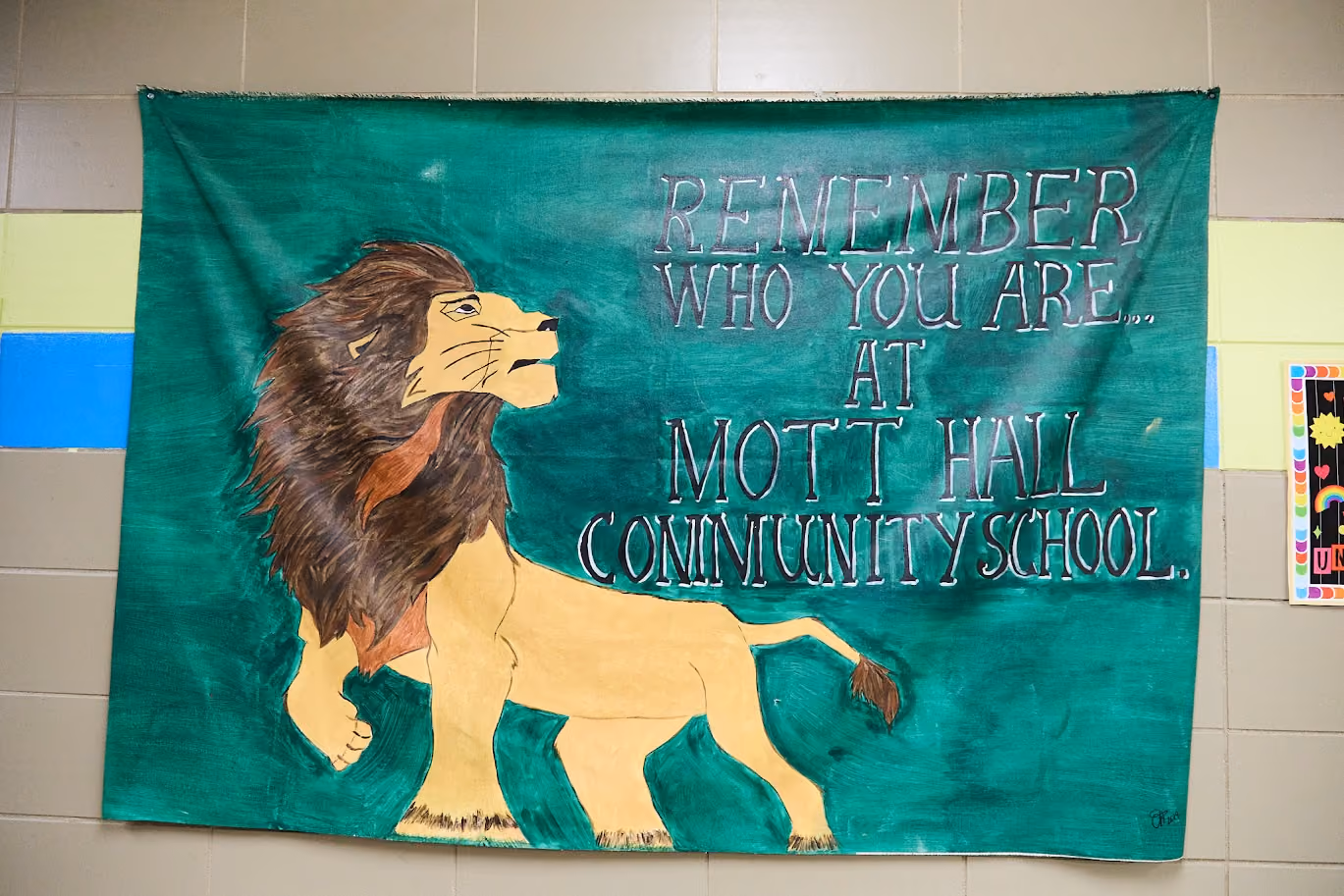 Hand-painted school banner with lion reading Remember Who You Are at Mott Hall Community School