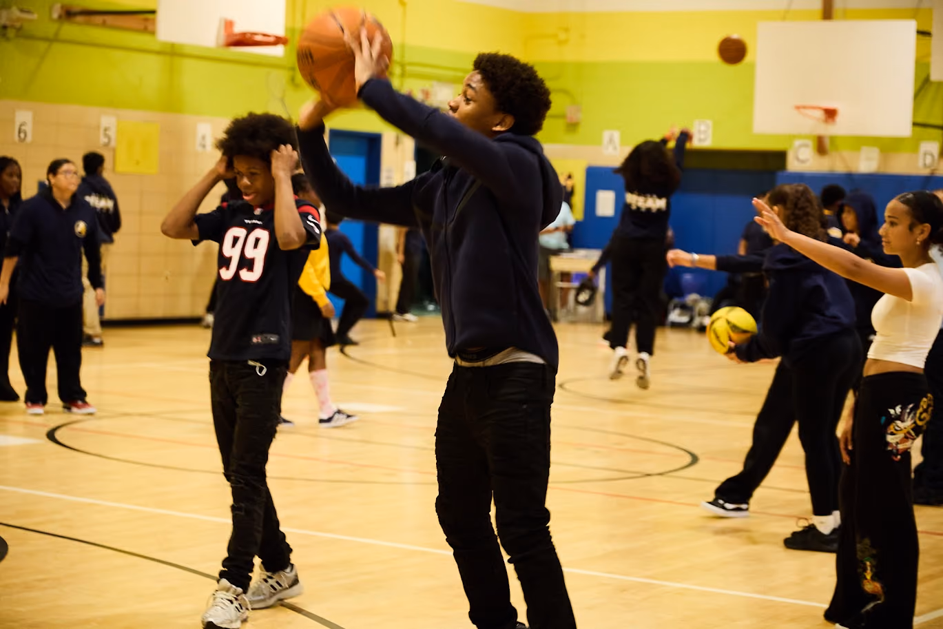 Students playing basketball in a school gymnasium during gym class