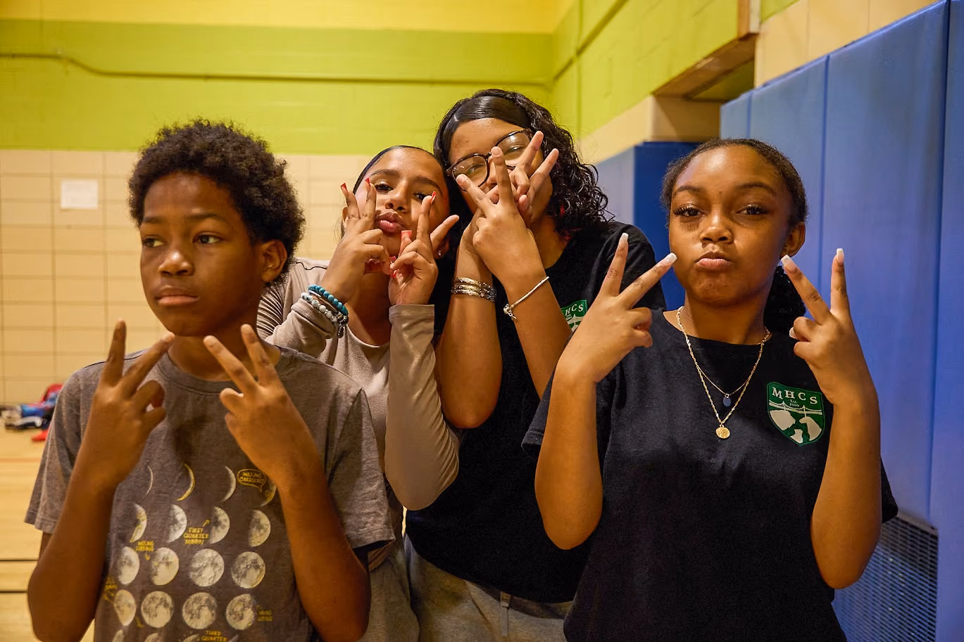 Four MHCS students posing with peace signs in school gym