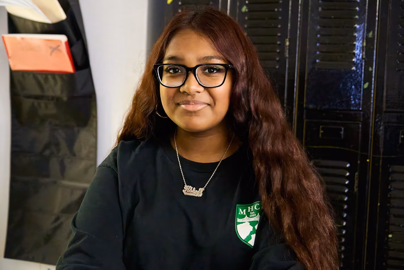 Smiling MHC student wearing school sweatshirt near lockers