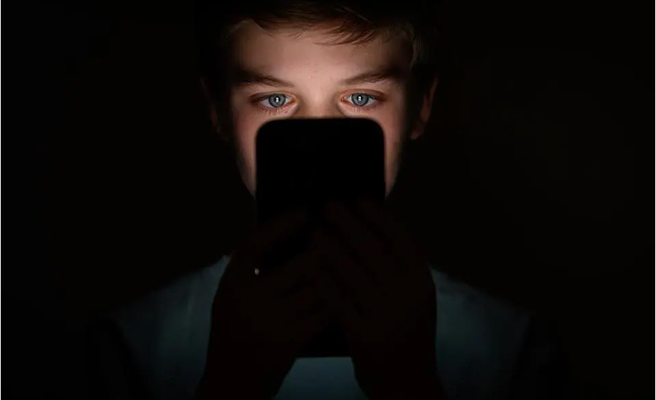 A kid looking at a cell phone.