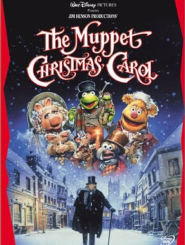 The Muppet Christmas Carol,' a Walt Disney Pictures and Jim Henson Productions film. The cover shows the Muppet characters floating in a snowy night sky above a Victorian-era street scene. Kermit the Frog dressed as Bob Cratchit is prominently featured in the center, along with Miss Piggy and other Muppet characters. Below them on the cobblestone street is a solitary figure in a long dark coat and top hat carrying a walking stick, representing Ebenezer Scrooge. The scene is set against illuminated shop windows and period architecture with falling snow. The title appears in decorative pink script lettering at the top, with the Disney logo and DVD marker visible on the cover's border.