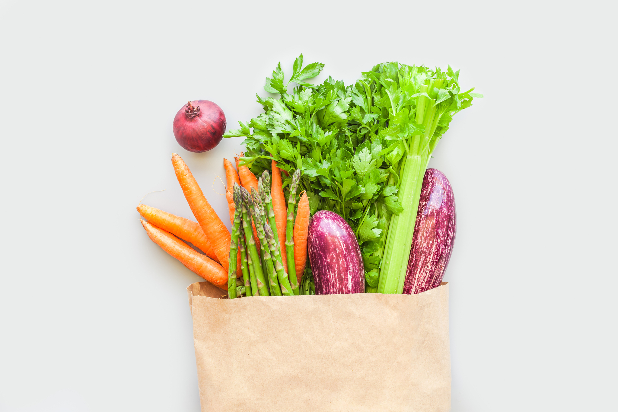 paper bag full of carrots, eggplant, celery, and onion