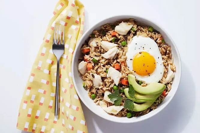 A bowl of rice with a fried egg and vegetablesAI-generated content may be incorrect.