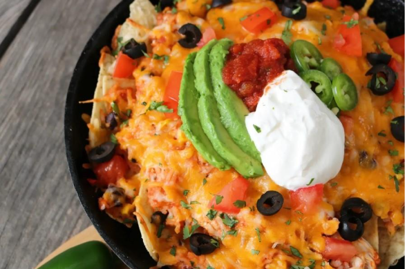A bowl of nachos with cheese and avocadoAI-generated content may be incorrect.