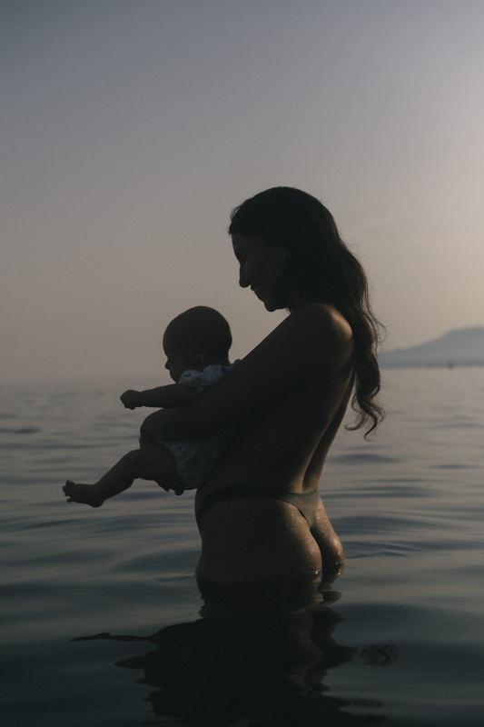 A mother holding her baby while standing in the ocean at Malaga beach 