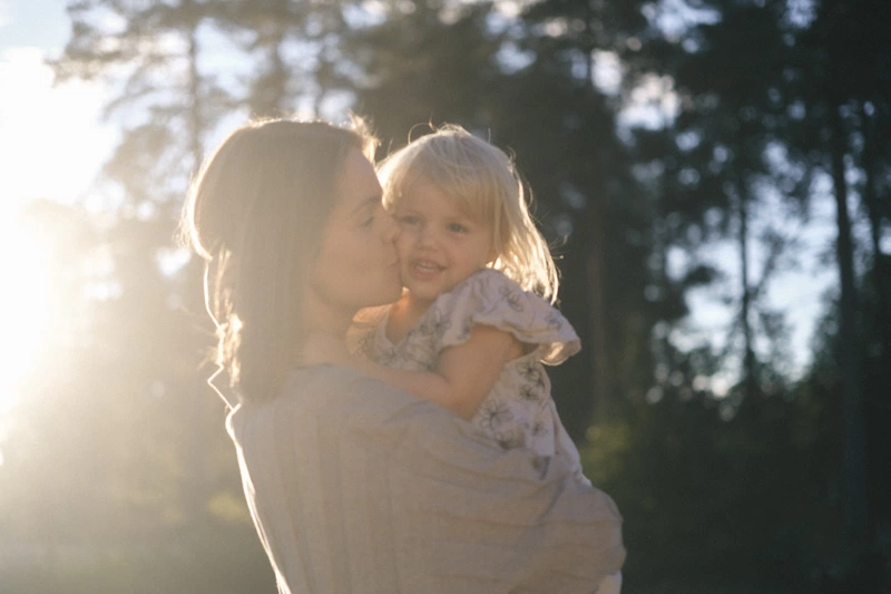 A mother kissing her daughter during a family photoshoot 