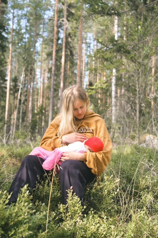 A mother breastfeeding her baby in the woods