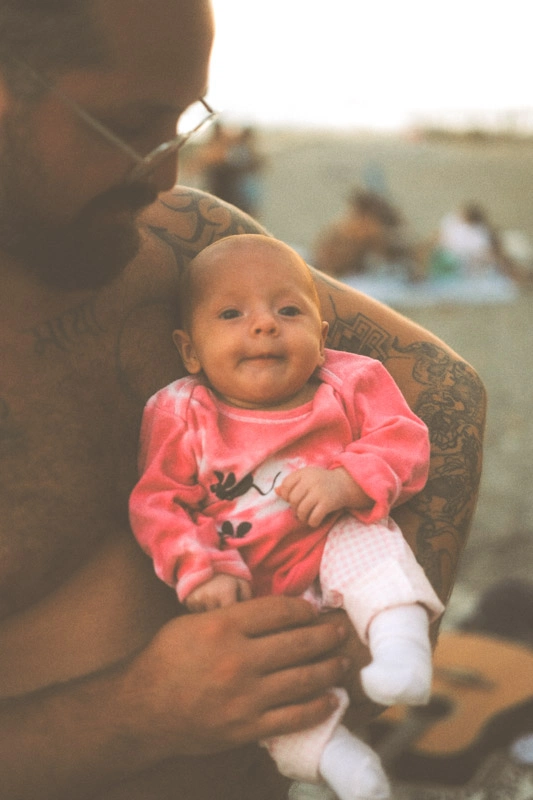 A dad holding his newborn daughter at a beach in Malaga