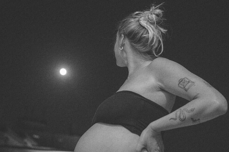 A pregnant women looking at the full moon
