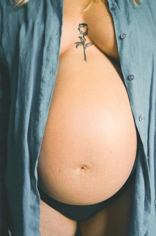 A pregnant women with bare belly and a open shirt