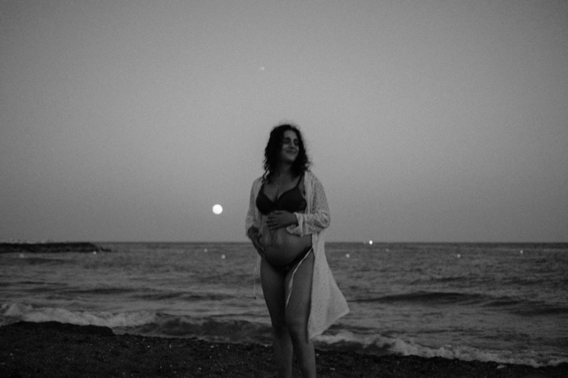Black and white photo of a pregnant women by the sea and a full moon in Malaga 