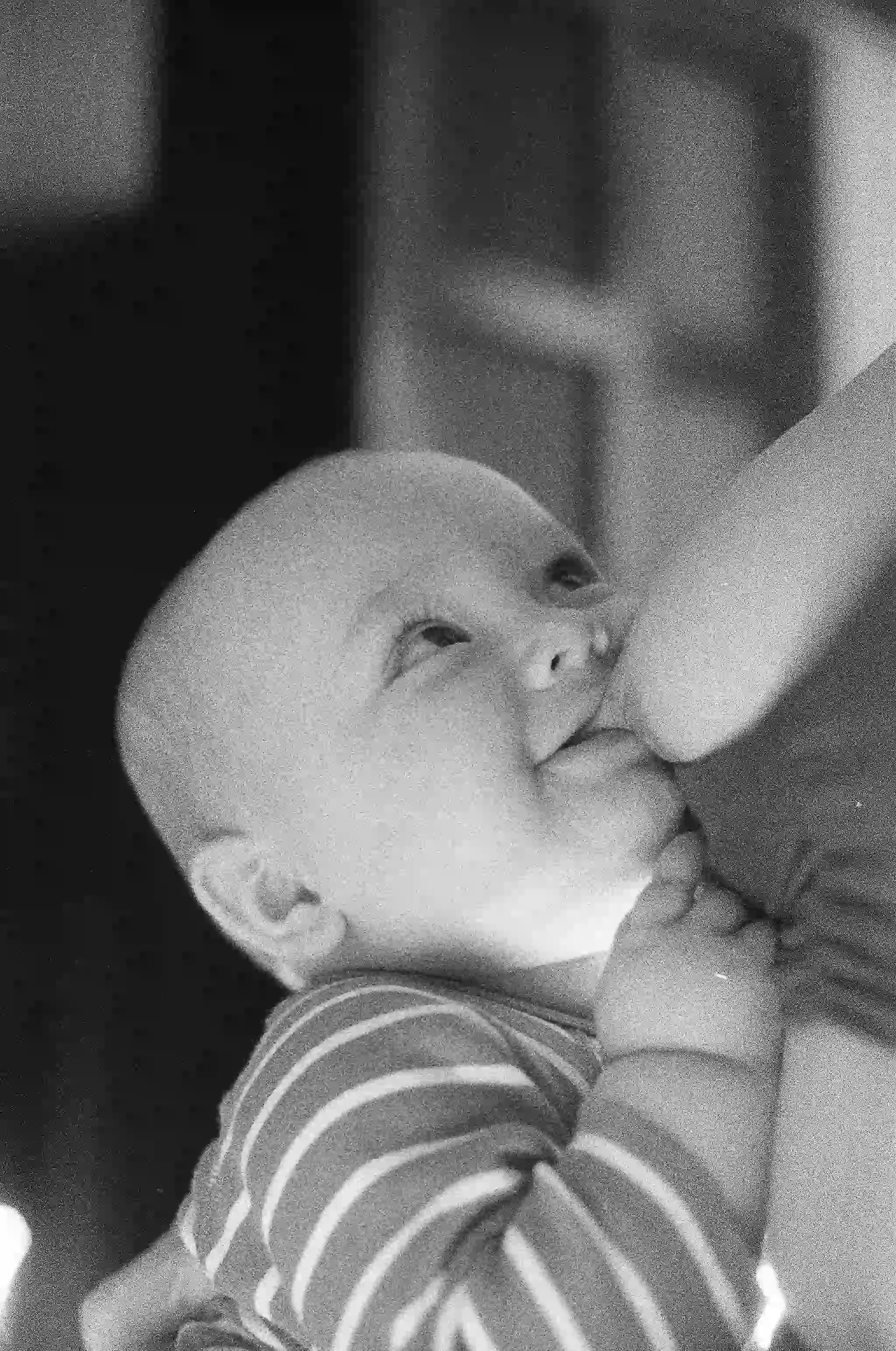 A black and white photo of a baby breastfeeding 