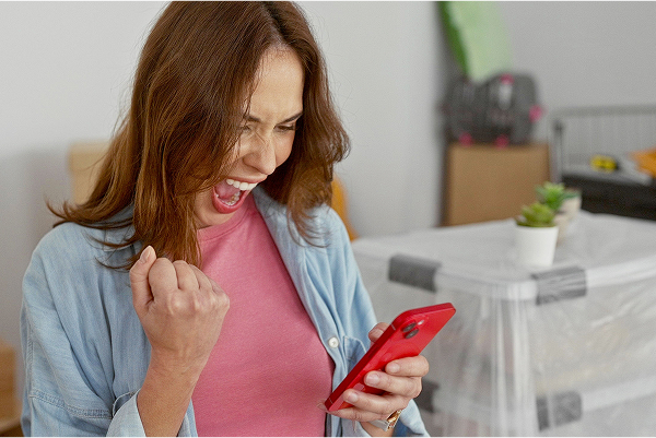 A woman looking at her phone and is excited. 