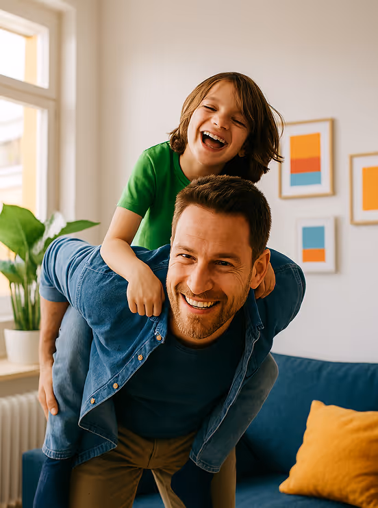 A son is sitting on the back of a father and they are both laughing.