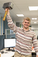 Man holding up a hammer over his head while smiling. 