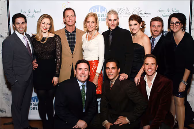 A group of the Broadway Dreams leadership team standing on a red carpet in front of the event's branded backdrop.