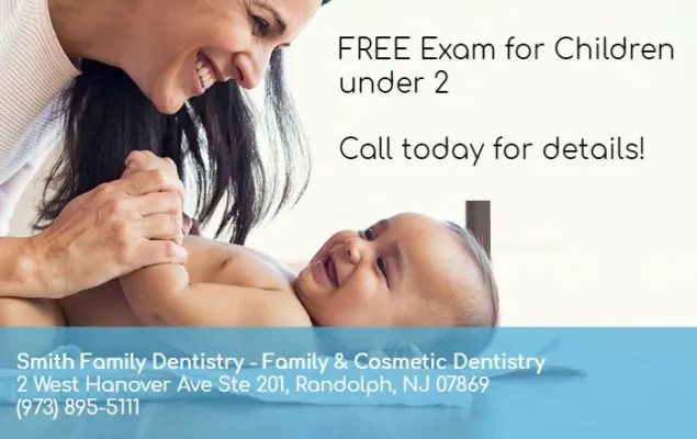 Smiling woman leaning over and holding hands with a happy baby lying down, with text offering a free exam for children under 2 from Smith Family Dentistry.