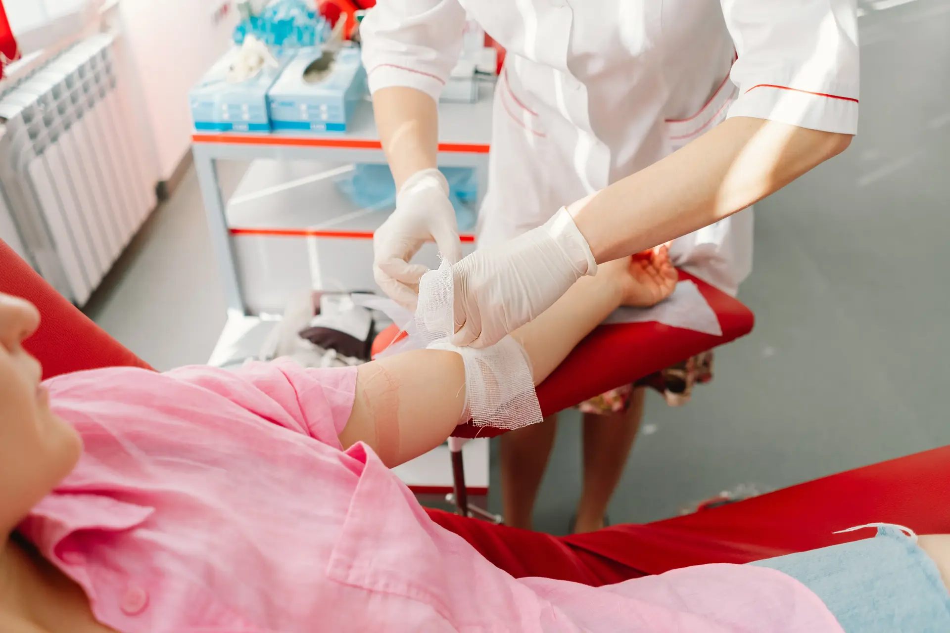 A phlebotomist drawing blood from a man’s arm.