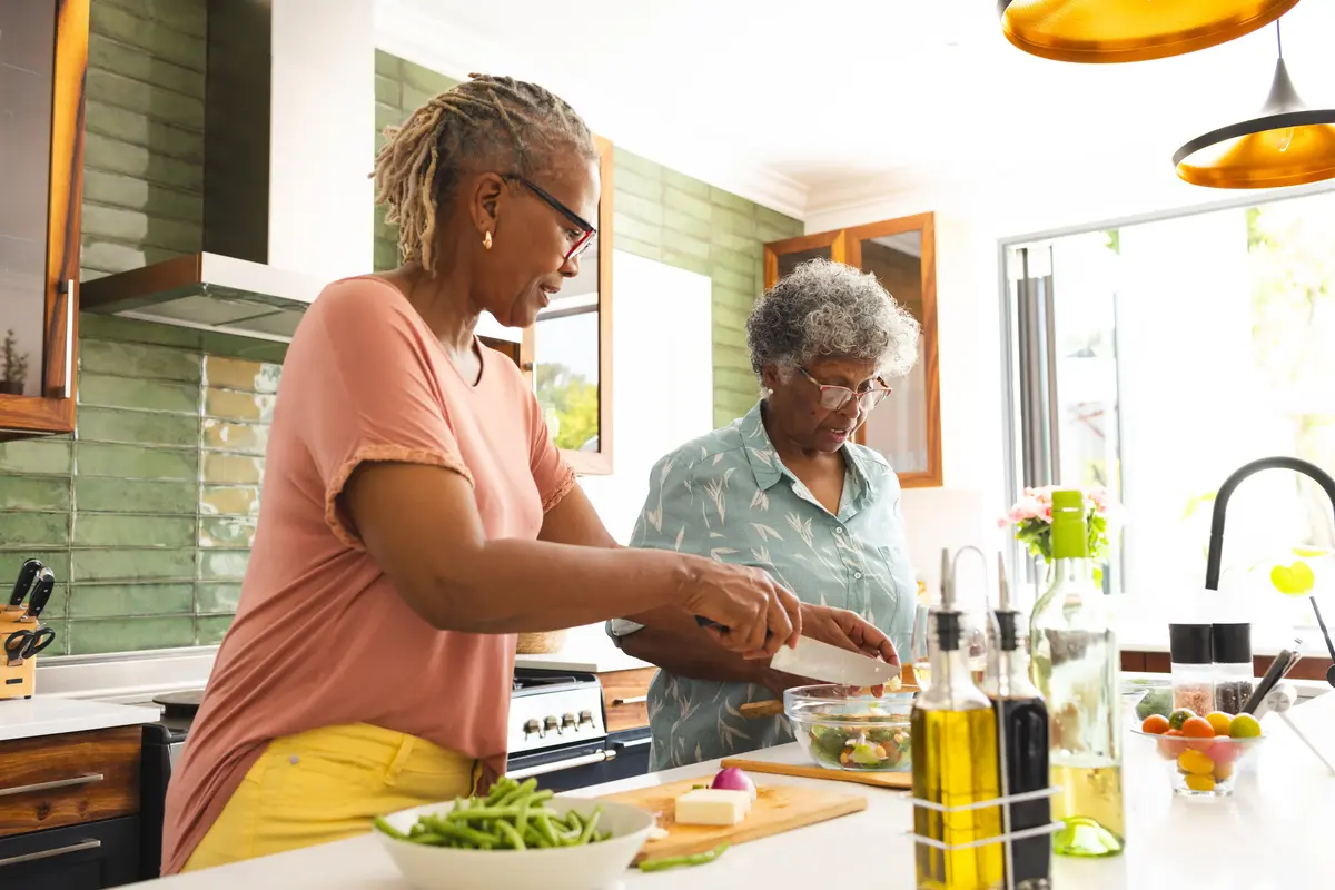 Two senior women cooking in a well-lit kitchen.