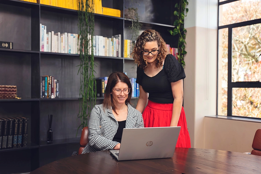 Two female lawyers looking at a computer, one is sitting and the other is standing