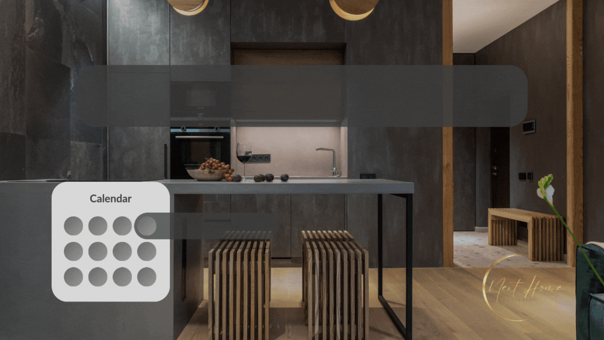 Modern kitchen with dark cabinets, a countertop island with two slatted wooden stools, a wine glass, grapes, and a doorway leading to a hallway with benches.