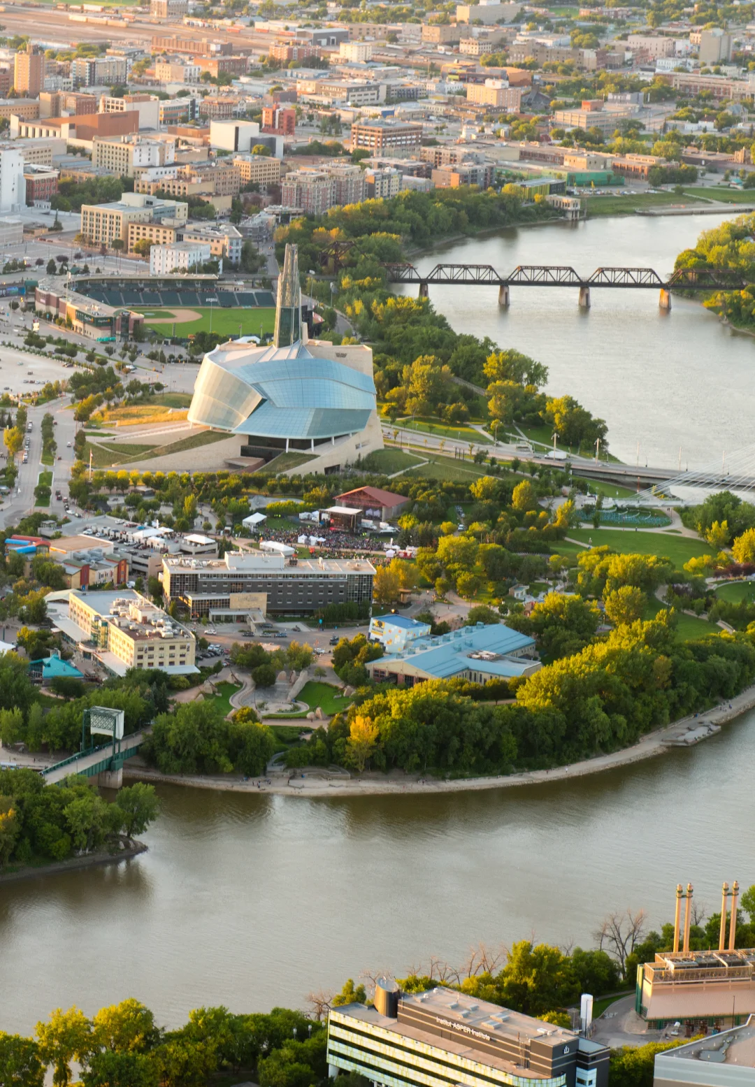 Aerial view of The Forks in Winnipeg, showing the river, green spaces, bridges, and Canadian Museum for Human Rights.