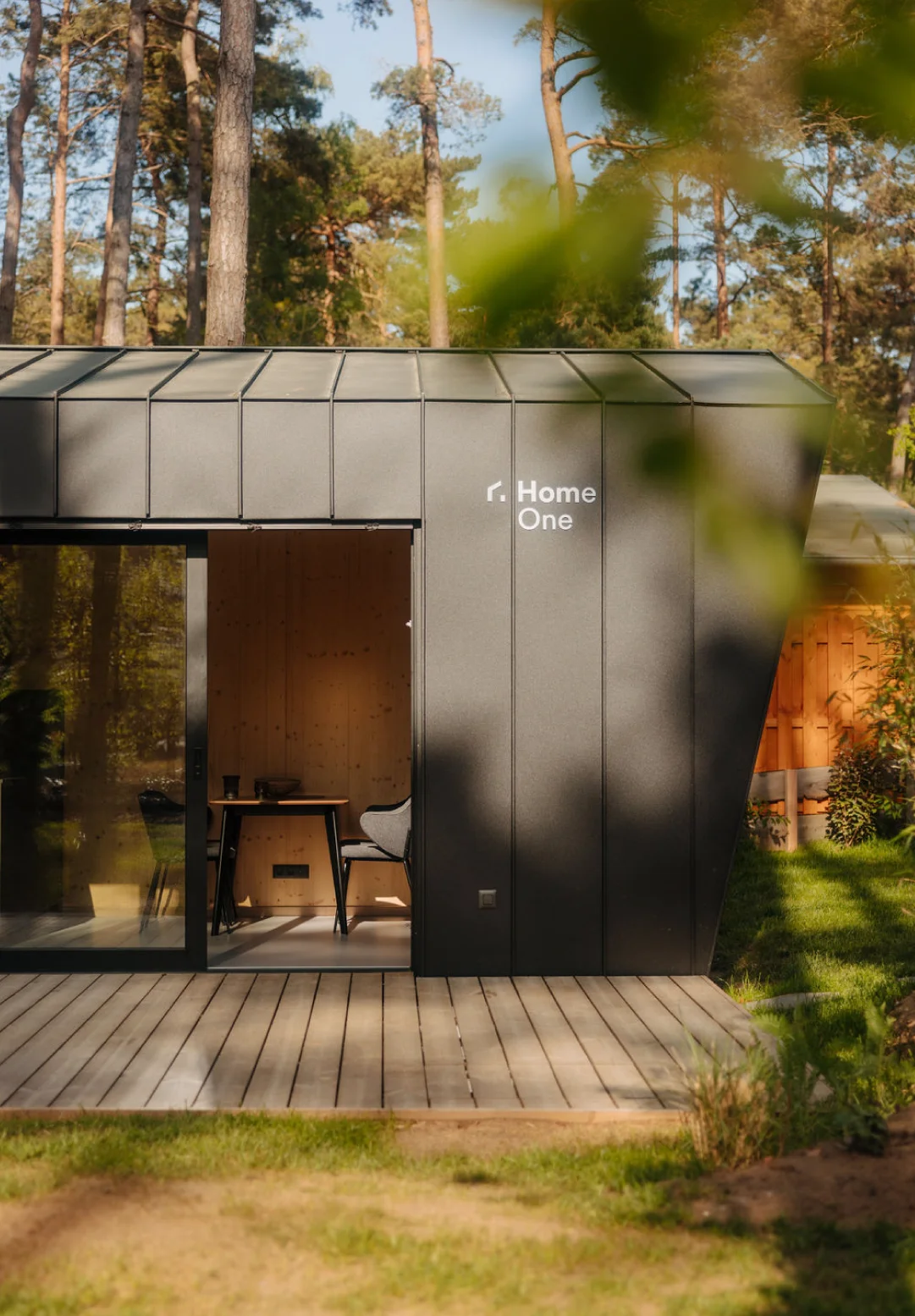 Exterior view of a modern Home One cabin surrounded by trees, representing boutique hospitality design and forest retreat branding.