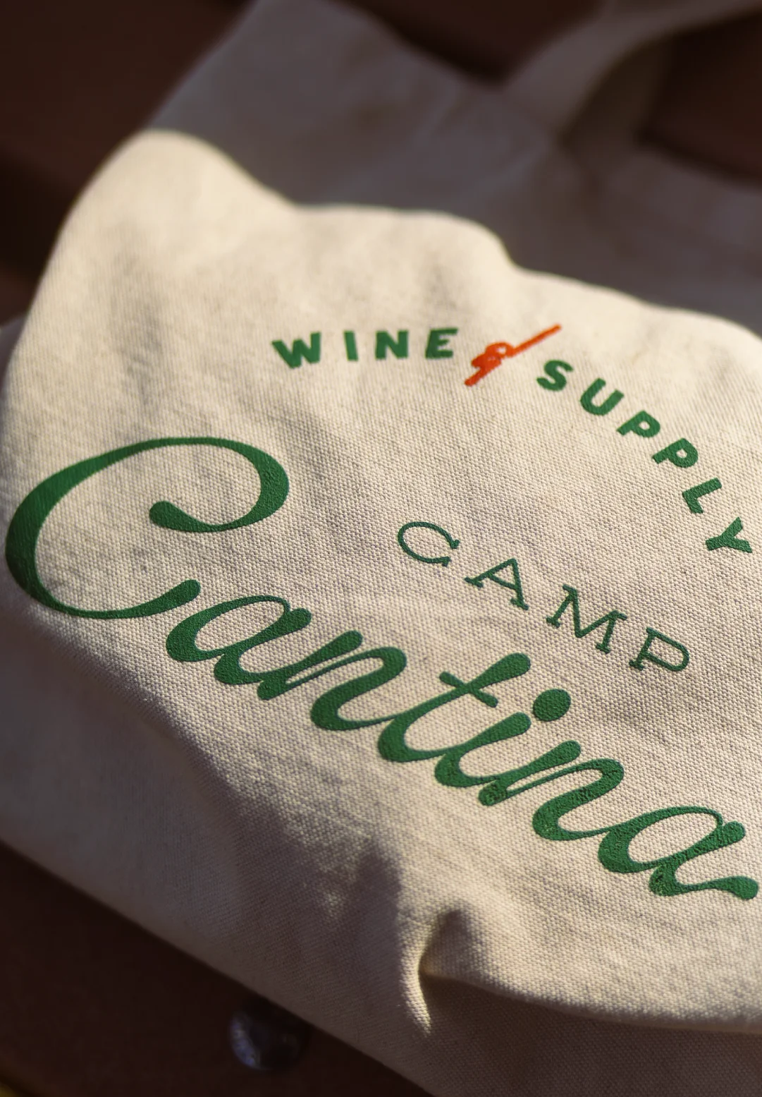 Branded Camp Cantina tote bag with “Wine Supply” graphic, photographed in warm light for restaurant and hospitality brand activation.