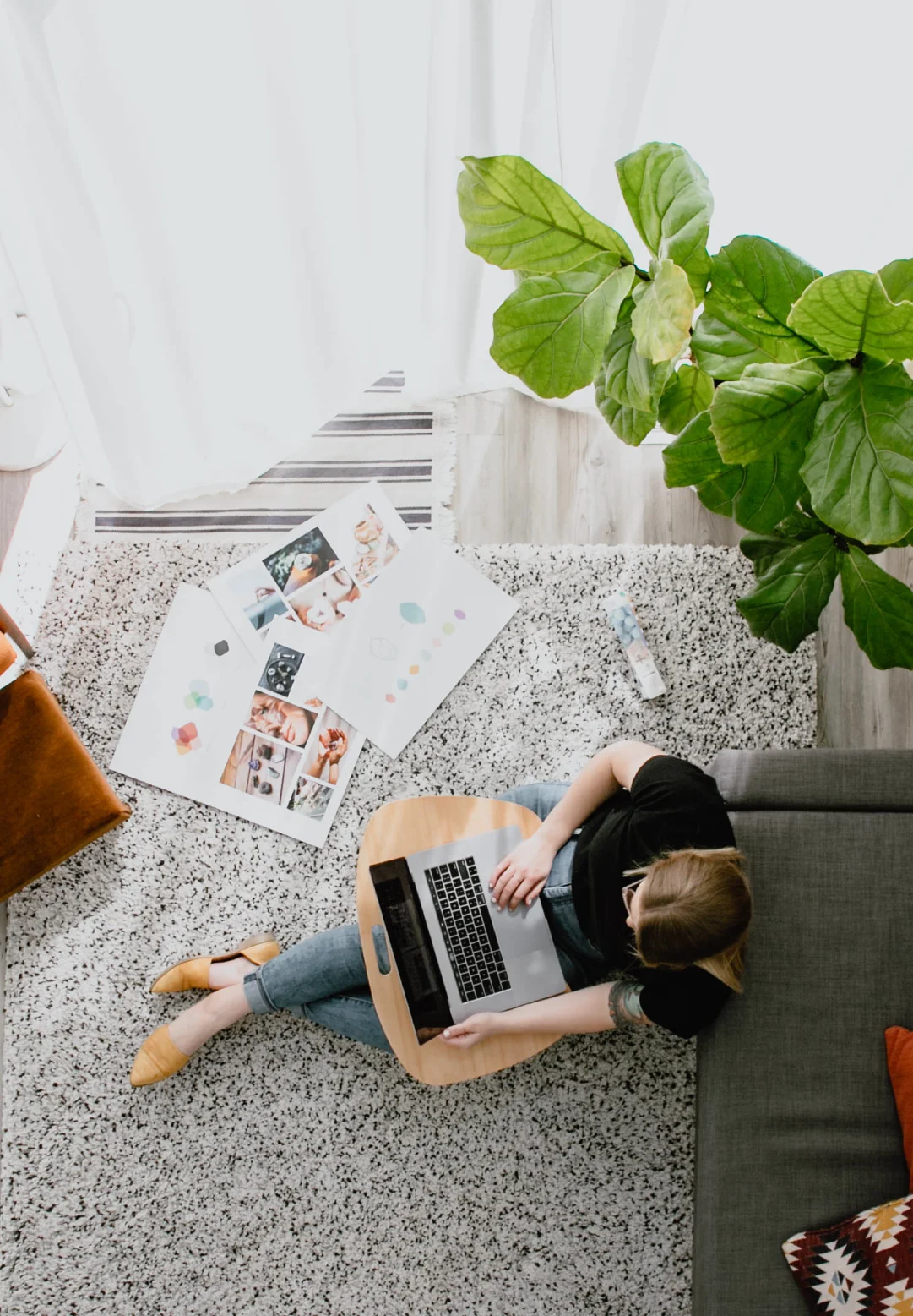 Overhead view of a designer working on a laptop beside brand mood boards and colour concepts in a bright studio workspace.