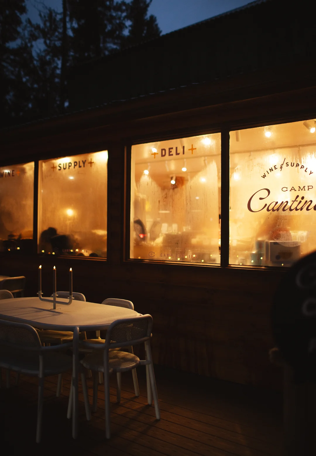 Warm evening view of Camp Cantina’s exterior windows and patio seating, showing restaurant and hospitality brand activation in a real guest setting.