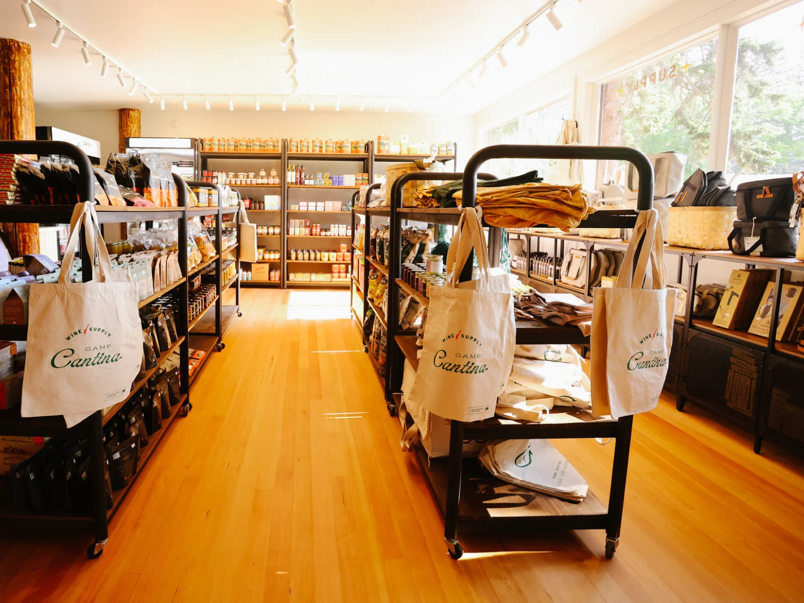 Interior of Camp Cantina’s wine and supply shop with branded tote bags, merchandise displays, and retail shelving for hospitality brand rollout.