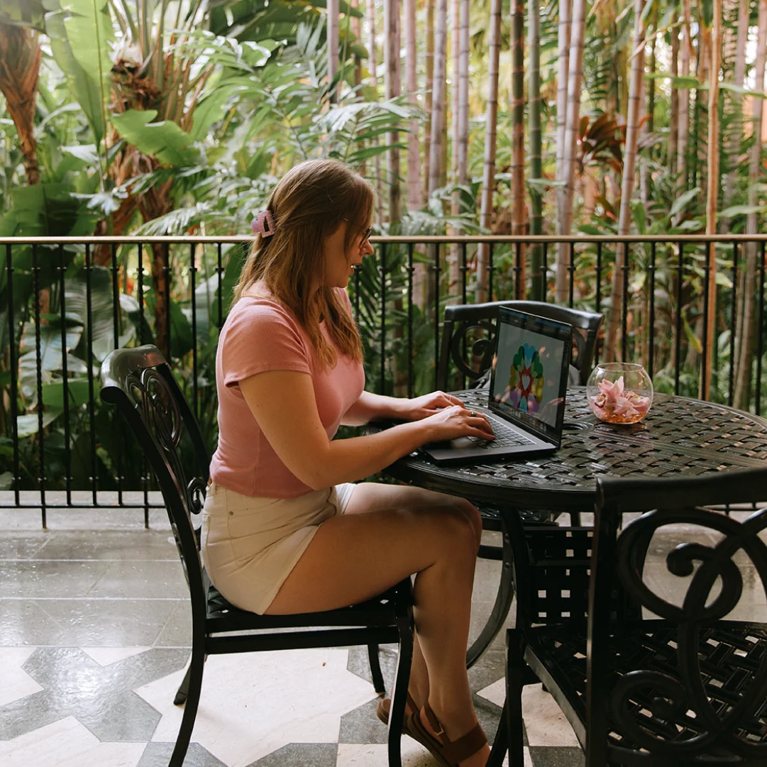 Creative director working on a laptop in a lush outdoor courtyard, reflecting place-based brand strategy for tourism and hospitality businesses.
